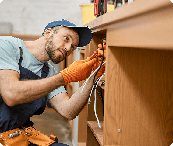 Handyman working on some wires under a cabinet