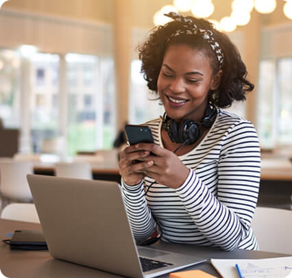 Woman sitting at desk smiling while texting on her smart phone